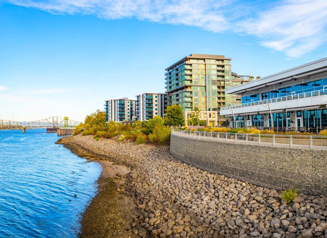 Vancouver, WA - Riverside Waterfront Development With Modern Buildings And A Rocky Shoreline Near A Bridge